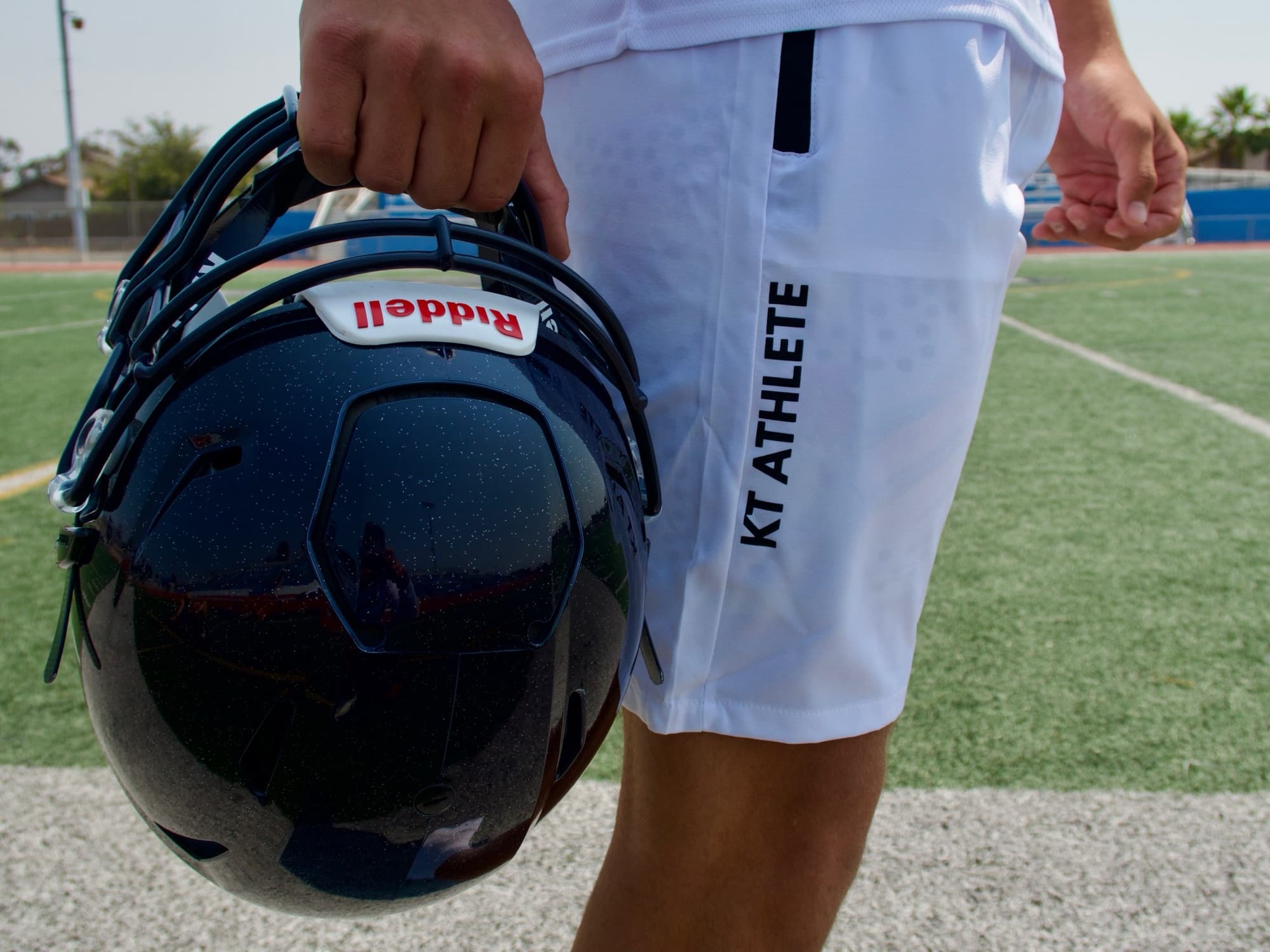 A KT athlete carries his helmet off the field